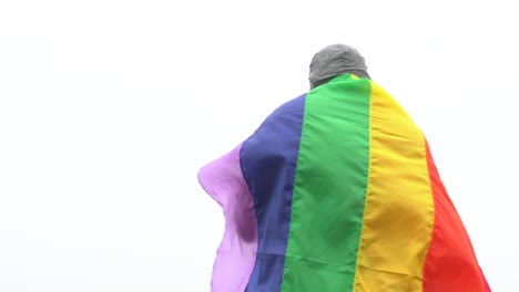 hombre-levantar-bandera-LGBTI-de-color-arco-iris-ondeando-en-duro-viento-en-el-mirador-de-alta-montaña