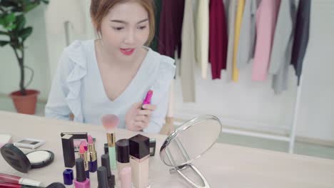 Beauty-blogger-present-beauty-cosmetics-sitting-in-front-camera-for-recording-video.-Beautiful-asian-woman-use-cosmetics-while-review-make-up-tutorial-broadcast-live-video-to-social-network-by-internet.