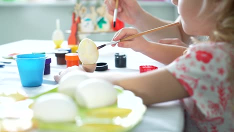 Woman-and-Daughter-Drawing-Smiley-on-Easter-Egg