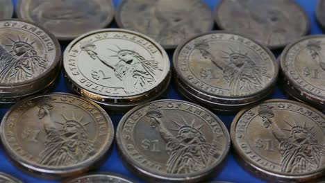 Monedas-americanas-de-un-dólar-en-el-fondo-de-papel-azul