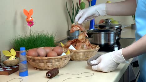 mano-de-mujer-preparan-huevos-de-Pascua-teñidos-con-cáscara-de-cebolla-cocina.-4K