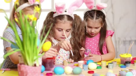 Happy-children-wearing-bunny-ears-painting-eggs-on-Easter-day.