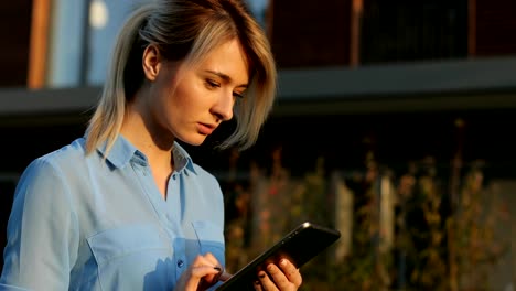 Close-up-portrait-of-a-beautiful-business-woman-holding-and-using-tablet-outside,