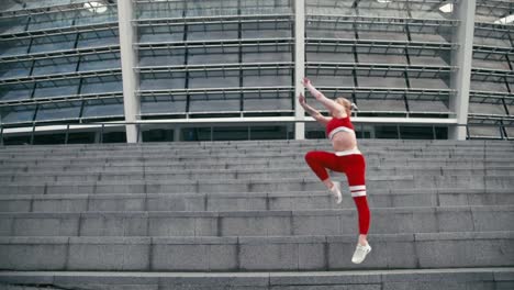 Mujer-sonriente-rubia-de-raza-mixta-vistiendo-ropa-deportiva-roja-haciendo-gimnasia