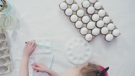 Niña-pequeña-pintando-huevos-de-Pascua-con-pintura-acrílica.