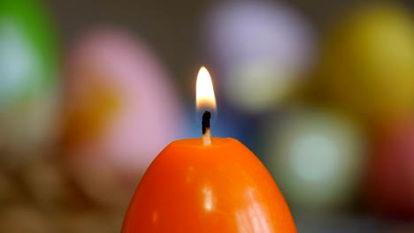 Candles-made-in-shape-of-easter-egg.-Orange-candles.-Female-hand-lights-candles.