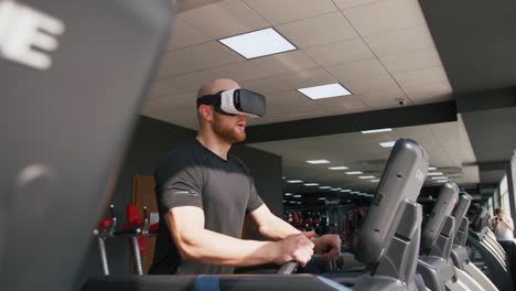 Joven-fuerte-haciendo-ejercicio-en-la-cinta-en-el-gimnasio,-usando-gafas-VR,-cámara-lenta