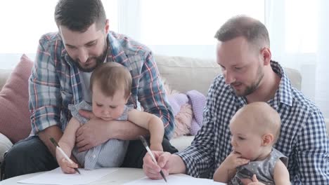 Two-fathers-with-baby-girls-drawing-on-paper