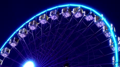 Beleuchtetes-Riesenrad-dreht-sich-gegen-einen-dunklen-Himmel.