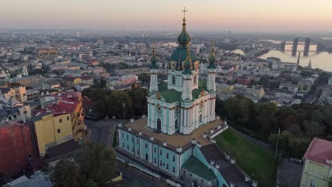 Flying-around-St.-Andrew's-Church-in-Podil-district-near-the-bank-of-Dnieper-in-Kyiv-(Kiev),-Ukraine-during-sunrise.-Aerial-shot,-4K