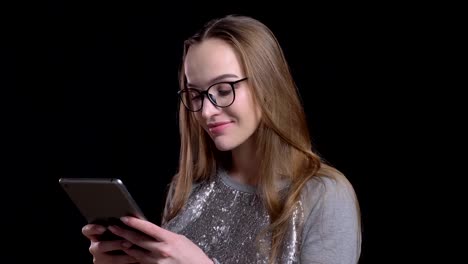 Closeup-shoot-of-young-attractive-hipster-female-in-glasses-using-the-tablet-with-background-isolated-on-black