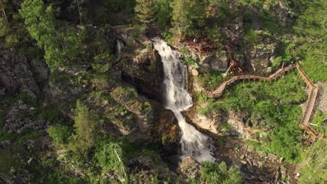 Drohne-fliegt-über-einen-grünen-Wald-mit-Wasserfall-im-Altai-Gebirge