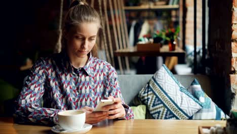 Attraktive-junge-Frau-mit-modernen-Smartphone-in-Café-berühren-Bildschirm