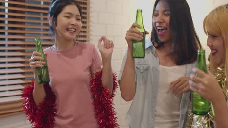 Grupo-de-mujeres-asiáticas-fiesta-en-casa,-mujer-bebiendo-cerveza-bailando-y-cantando-teniendo-divertidos-juntos-en-la-sala-de-estar-en-la-noche.-Adolescentes-jóvenes-amigos-juegan-juego,-celebran-el-concepto-de-vacaciones.-A-cámara-lenta.