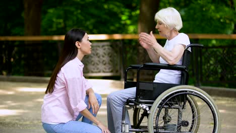 Voluntario-hablando-con-mujer-llorando-en-silla-de-ruedas,-apoyo-psicológico,-parque