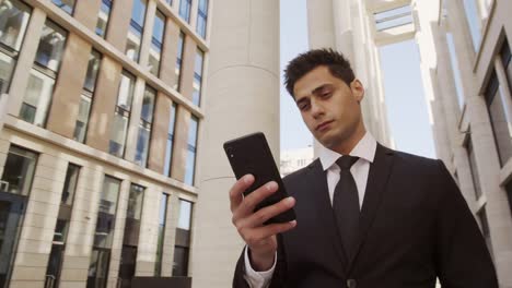 Attraktiver-Geschäftsmann-mit-Telefon-in-Downtown