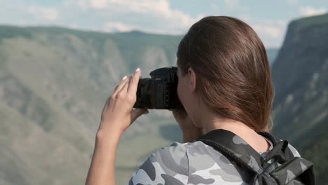 Female-traveler-takes-beautiful-pictures-using-the-camera-while-standing-at-the-peak-of-the-mountain.-Close-up