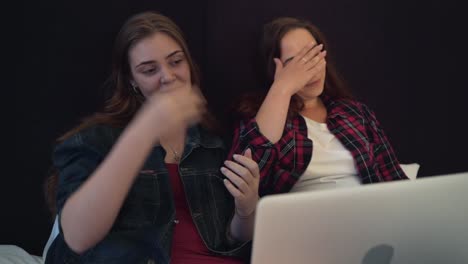 Two-attractive-young-women-in-bed-at-home-with-laptop.-Friendship-or-female-couple-concept