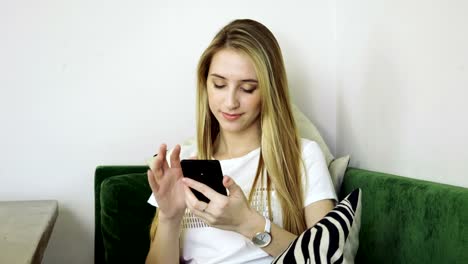 Joven-mujer-sonriente-usando-el-teléfono-inteligente,-enviando-mensajes-de-texto-en-el-teléfono-móvil-en-la-cafetería-moderna.-4K