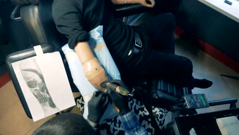 View-from-above-of-male-prosthetic-arm-getting-tattooed