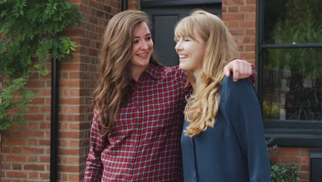 Portrait-Of-Excited-Gay-Female-Couple-Standing-Outside-New-Home-Together