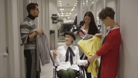 Mujer-en-silla-de-ruedas-elegir-camisa-en-la-tienda-con-la-ayuda-de-amigos