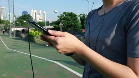 Mujeres-atletas-asiáticas-que-utilizan-teléfonos-inteligentes-comprobando-a-la-frecuencia-cardíaca-después-de-correr.-Jogging-estilo-de-vida-de-entrenamiento-en-la-calle-al-atardecer.-Estilo-de-vida-saludable.