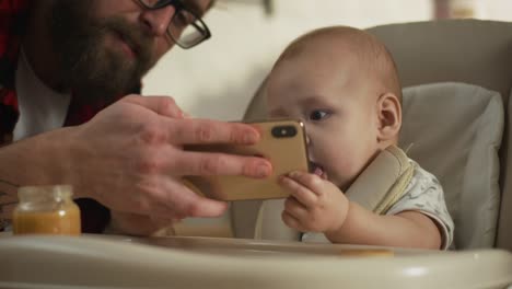 Padre-mostrando-teléfono-inteligente-a-bebé