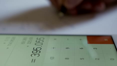 Man-accountant-hand-holding-pen-counting-on-calculator-on-smartphone.-Businessman-Doing-Calculations