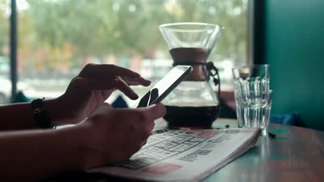 Freshly-brewed-coffee-and-a-newspaper.-Woman-with-cell-phone