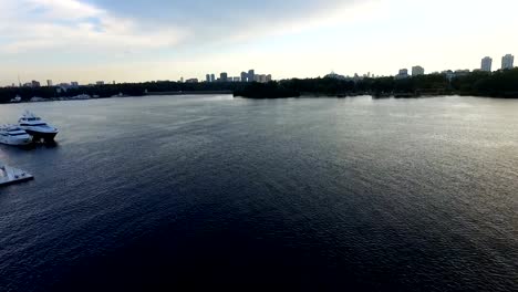 Shooting-bird's-eye.-Flying-drone-slowly-flying-over-blue-water.-Beautiful-hotel-on-the-banks-of-the-river.-Yacht-dock.4k-resolution.-Calm