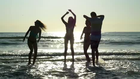 Group-of-four-friends-dancing-on-the-shore-of-the-sea