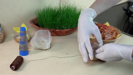 hands-with-gloves-put-onion-shells,-rice-and-egg-into-sock-and-string