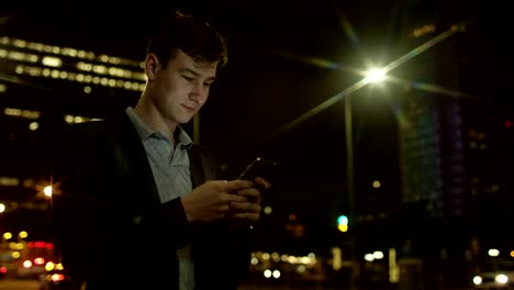 Handsome-guy-is-typing-a-text-message-while-standing-on-a-street