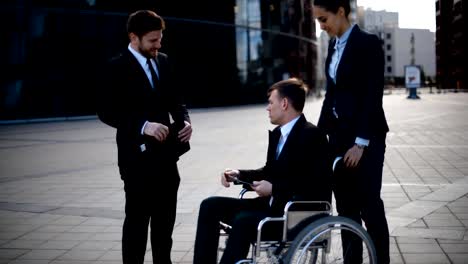 Young-disabled-entrepreneur-businessman-talk-with-his-coworkers-and-sign-textpad-docs