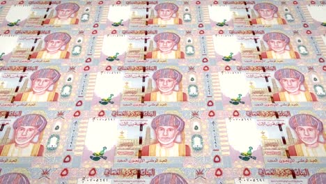 Series-of-banknotes-of-five-omani-rials-of-the-Central-Bank-of-Oman-rolling-on-screen,-coins-of-the-world,-cash-money,-loop