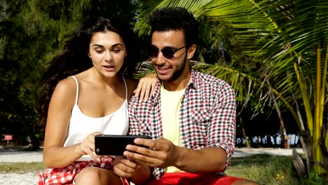 Couple-Using-Cell-Smart-Phone-Take-Selfie-Photo-Outdoors-Under-Palm-Trees-On-Beach,-Happy-Smiling-Man-And-Woman