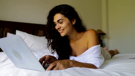 Mujer-joven-con-Laptop-computadora-feliz-riendo-hermosa-chica-acostado-en-cama-en-dormitorio-por-la-mañana