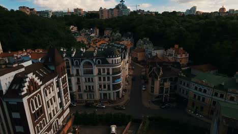 Zángano-de-la-cámara-se-mueve-bajo-techos-de-edificios-en-antigua-europeas-callejuelas-con-casas-de-colores-y-los-peatones-al-atardecer-4K