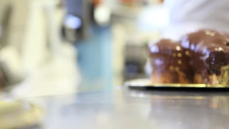 pastry-chef--hands-glazed-Easter-sweet-bread-cakes-with-chocolate,-closeup-on-the-worktop-in-confectionery