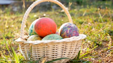 Close-up-of-basket-with-colourful-a-easter-eggs-on-grass-in-sunshine-background