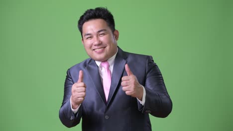 Young-handsome-overweight-Asian-businessman-against-green-background