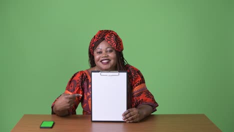 Overweight-beautiful-African-woman-wearing-traditional-clothing-against-green-background