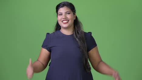 Young-overweight-beautiful-Indian-businesswoman-against-green-background