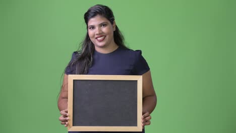 Young-overweight-beautiful-Indian-businesswoman-against-green-background