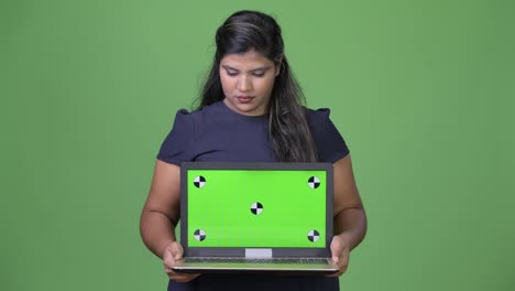 Young-overweight-beautiful-Indian-businesswoman-against-green-background