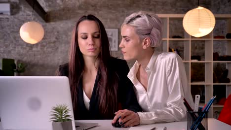 Two-young-charming-lesbians-working-in-office,-woman-flirting-with-woman,-touching-her-hand,-seductive-and-sexy