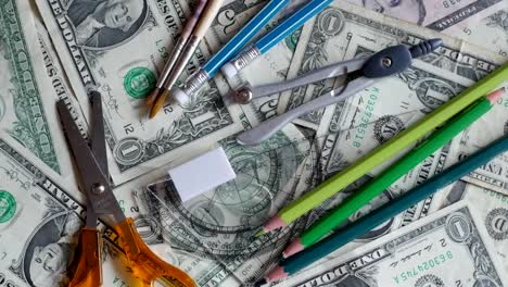 high-school-expenses,-concept,-pencils-on-money,-dollars,-rotating,-turning,-from-above