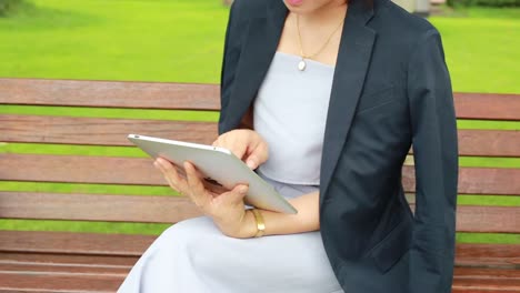 Junge-attraktive-Frau-mit-Tablet-PC-sitzen-im-Garten