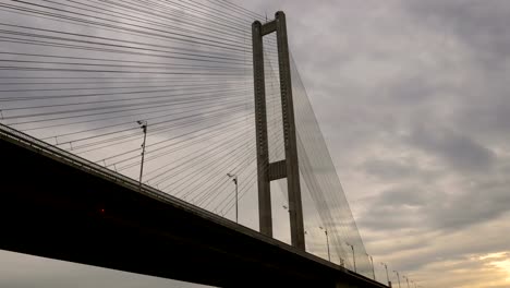 Blick-unter-die-großen-Hochbrücke-mit-Laternen-über-den-Fluss.-Architektonische-Gebäude-verbindet-die-beiden-Ufer-der-Stadt.-Massive-Struktur.-Zu-Fuß-auf-dem-Schiff-auf-dem-Wasser.